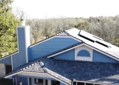 A blue house with a roof that has been painted.