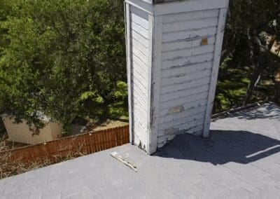 A white door of an old building next to trees.