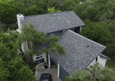 A house with trees in the background and a car parked on the driveway.