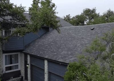 A house with trees and a roof that has been covered in shingles.